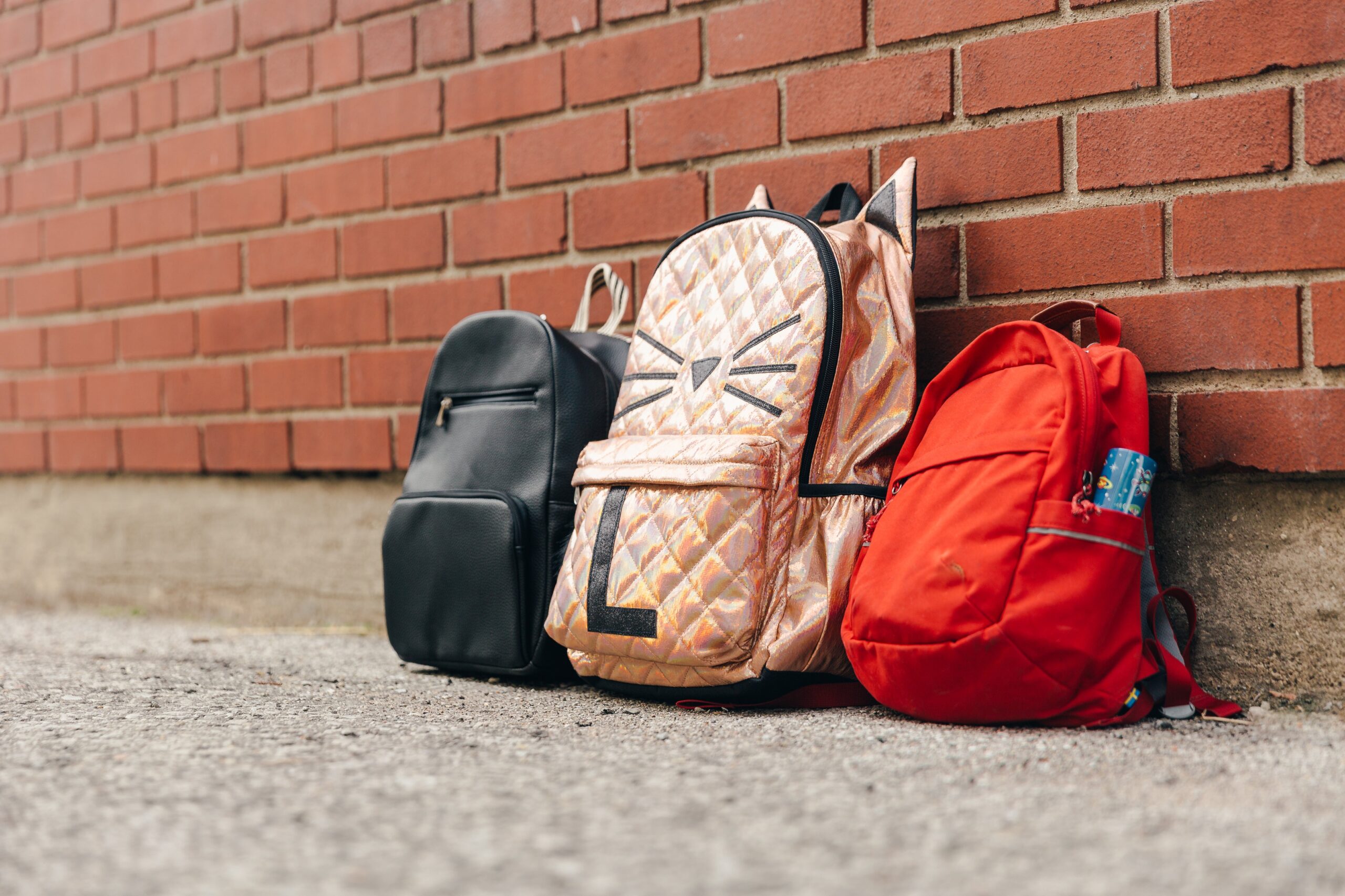 Trois sacs à dos pour enfants et un mur de briques